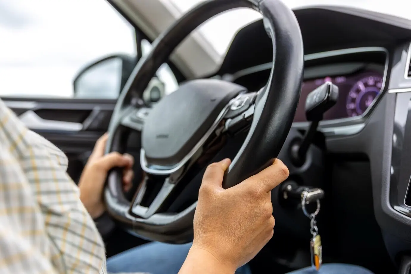 Fahrer am Steuer mit den Händen am Lenkrad in einem modernen Fahrzeuginnenraum.